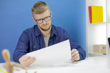 Young handsome animator designer in creative process, working on creating heroes, draws pencil...