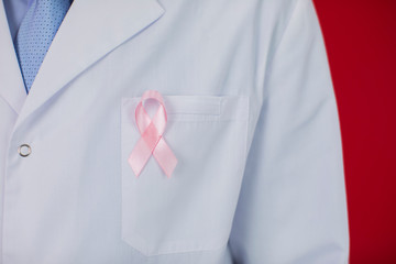 40s medical doctor with red ribbon for AIDS HIV awareness on red background close up isolated....