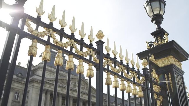 A smooth travelling shotof the golden fence at the entrance of the Royal Palace in Brussels, Belgium. The belgian flag is waving on top of the building wich indicates the king is in Belgium.