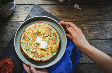 Thin pancakes with herbs. Salty Pancakes with green onions. Wood background. Vintage background. Delicious food for a bite to eat. Free space for text. Top view. Blue linen napkin. Woman hands