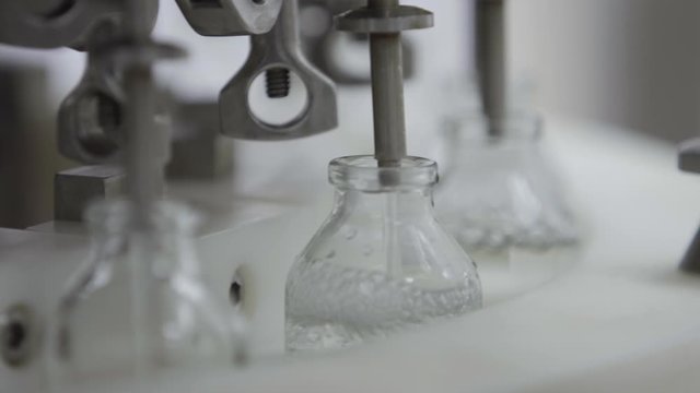 glass bottles on a medical solution conveyor at filling station close up selective focus medical industry