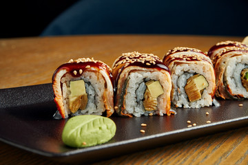 Traditional japanese sushi roll with eel, cucumber, cream cheese and salmon on a black plate. Close up. Food photo for menu