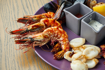 Plate with deep-fried seafood - mussels, octopuses, scallops, squid and shrimp. Antipasto. CLose up view. Wooden background