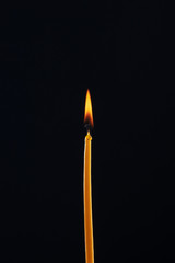 Burning church candle on a dark/black background.