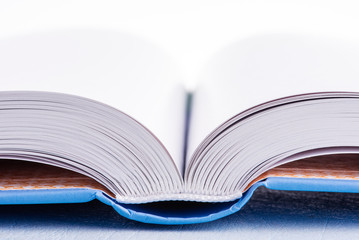 Open book close-up lying on blue wooden table with white background