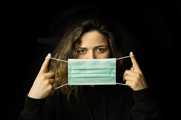 Naklejka premium studio portrait of young woman wearing a face mask, isolated on black background