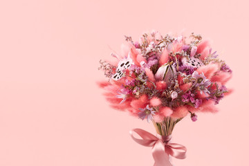 Beautiful bouquet of pink dried flowers on a pink background, close-up
