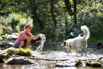 Woman and her dog in the summer river.