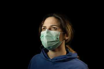 Girl in respiratory mask. Masked woman looks at camera. Cold, flu, virus, tonsillitis, respiratory disease, quarantine, epidemic concept.