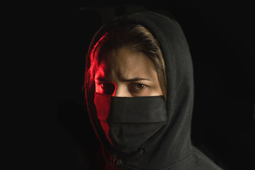 Portrait of beautiful woman with a black mask on the black background. Black and red portrait