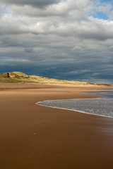 View of waves hitting Balmedie beach on a cloudy day