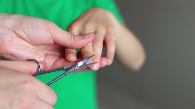 Mom boy cuts his nails with scissors. The child is cut nails
