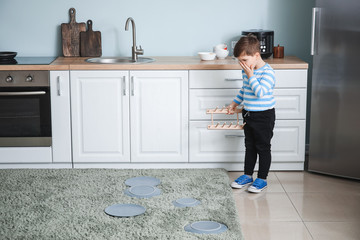 Shocked little boy with fallen plates at home