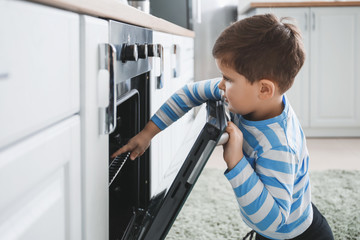 Little boy playing with electric oven at home © Pixel-Shot