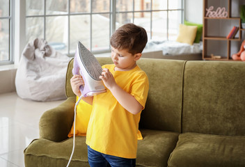 Little boy playing with electric iron at home