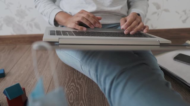 Mom and son sit at home quarantine because of coronavirus COVID19. Mother works remotely with laptop, son plays with toy blocks. Self isolation at home.