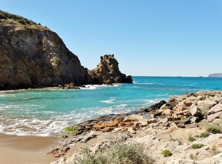 Fototapeta na wymiar Panorama casi lunar con paisaje de playa de arena rojiza y paraje desértico con acantilados en la costa del Mar Mediterráneo dentro del Parque Regional de Calblanque en Murcia