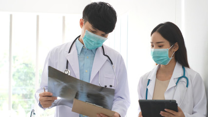 Doctor and nurse discussing the diagnosis of a patient for the future advice for his treatment during walking in a hospital ward. Concept of medicine.Busy Doctors Talk, Using Tablet Computer 