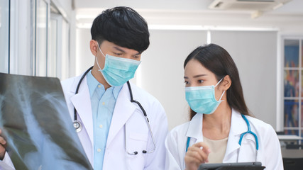 Doctor and nurse discussing the diagnosis of a patient for the future advice for his treatment during walking in a hospital ward. Concept of medicine.Busy Doctors Talk, Using Tablet Computer 