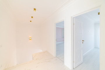 White empty corridor with white doors and gold fittings and ceiling lights. Home design