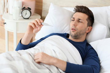 Young man ill with flu lying in bed