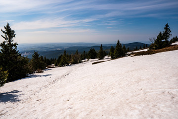 last snowfall at the end of winter with a well-trodden hiking trail Jeseniky mountains with a beautiful sky at the end of winter