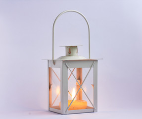 burning candle inside a lantern on white background