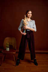 Fototapeta premium Gorgeous young female in classic suit, black shoes and grey coat. Vintage chair. Woman's clothes.