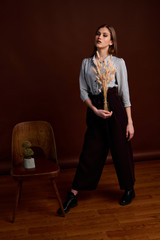 Fototapeta premium Gorgeous young female in classic suit, black shoes and grey coat. Vintage chair. Woman's clothes.