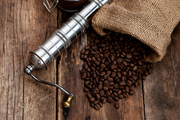 Bag of coffee on a wooden table. Coffee beans ground in a jar. Manual coffee grinder. Top view, place for text. Brown background. Packing coffee in a pack. White up with a drink.