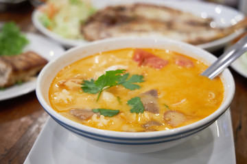 Large bowl of delicious spicy Thai soup Tom Yam as a main dish for lunch.