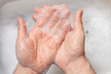 Fototapeta premium a man washes his hands over water with foam