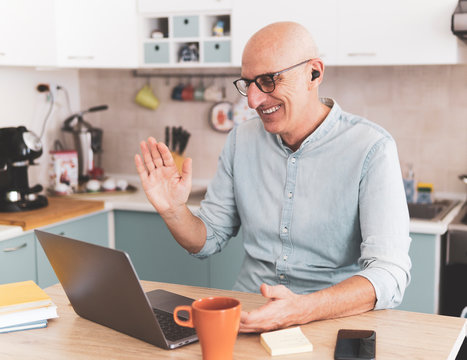 Businessman in video call with colleagues during quarantine isolation - Happy manager works from home and laughs - remote work and online conference concept.
