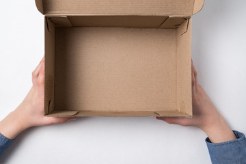 Children's hands holding an open cardboard box. Empty box, white background.