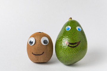 Avocado and kiwi with funny faces on white background. Products with Googly eyes