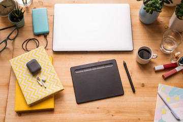 Notebooks with cordless earphones, folded laptop, pad with stylus, etc on table