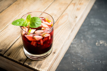 Old fashioned cocktail with blackberry liqueur and apple slices on rustic background. Selective focus. Shallow depth of field.