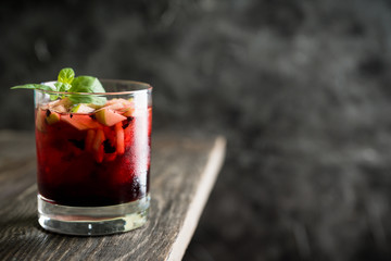 Old fashioned cocktail with blackberry liqueur and apple slices on rustic background. Selective focus. Shallow depth of field.