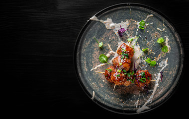 deep fried meatballs in plate on black wooden table background