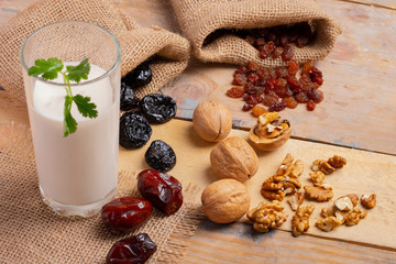 dried fruits and nuts with milk on wooden background