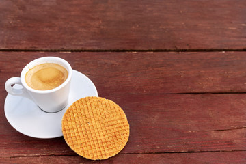 Cup of coffee and hohey wafer on wooden background.