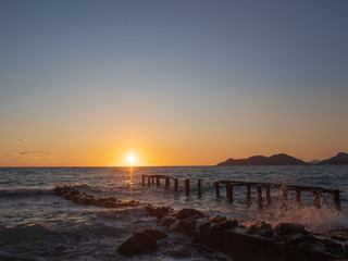 Epic sunset (dawn) on the sea. Waves are breaking on stones.
