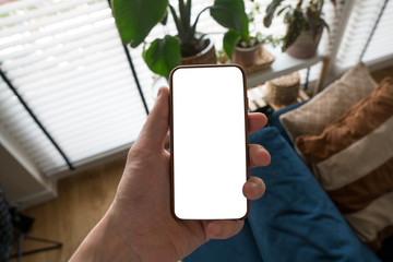 Working on mobile. Taking a picture. Phone in hand with white screen. Blur background. Mockup for mobile design. Close up.