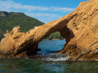 View of the coast from the sea. Rock arch. Bright sunny summer day.