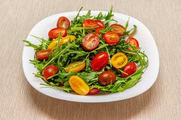 home cooked salad of arugula and red, brown and yellow cherry tomatoes close up