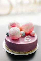 лиловый торт с розовыми и голубыми шоколадными шарами на черном столе