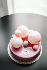 purple cake with chocolate balls of different sizes and the number six