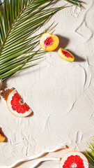 Beach vacation. A palm leaf and juicy fruits lie on white fine sand. Desktop wallpaper.