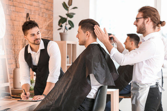 Young man with professional hairdresser and model during courses in salon