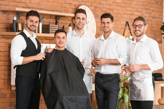Professional hairdresser teaching young men in salon